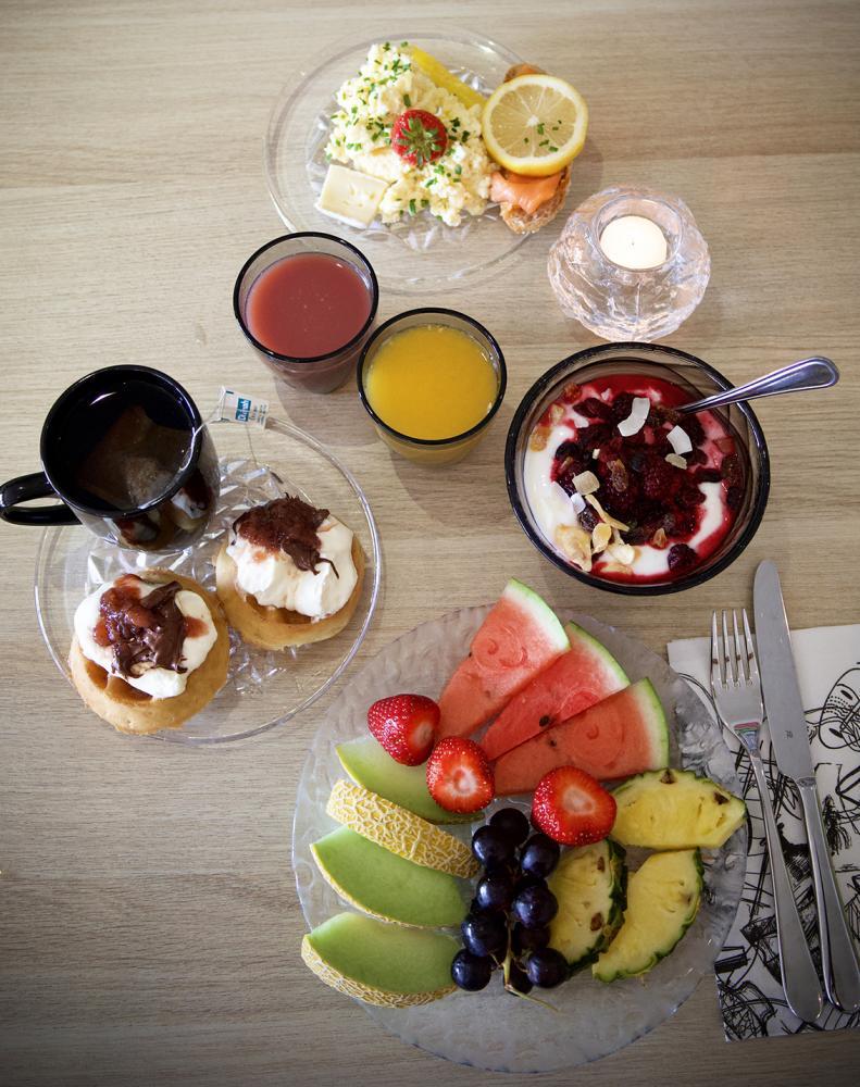 Uppdukad frukost bestående av färsk frukt, juice, kaffe, äggröra & våfflor med sylt